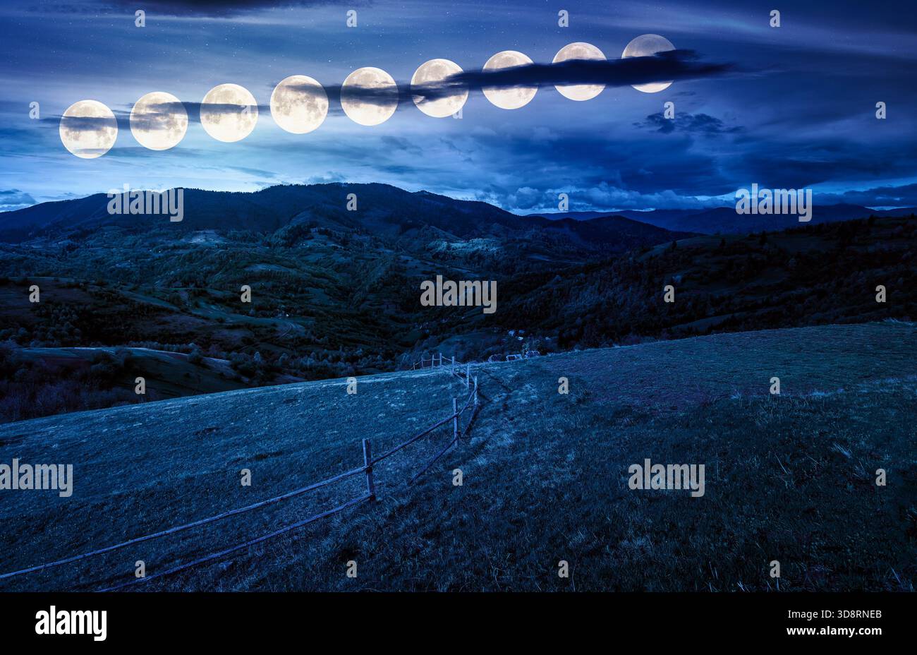 wooden fence on hillside with rural field in mountains at night. beautiful countryside landscape with rolling hills and pasture in spring in full moon Stock Photo