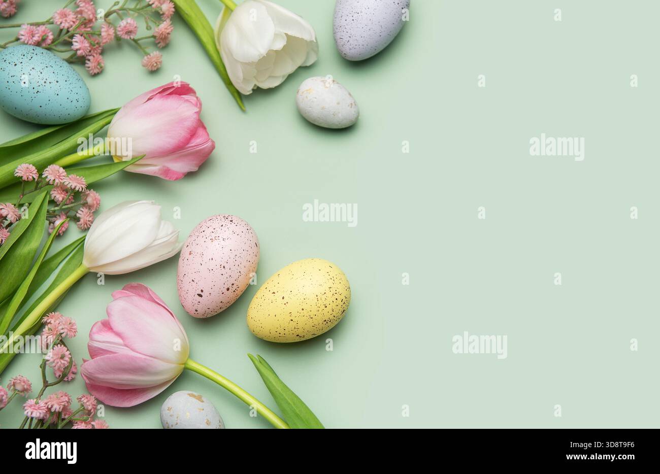 Colorful easter eggs and tulips creating a border on a pastel green ...