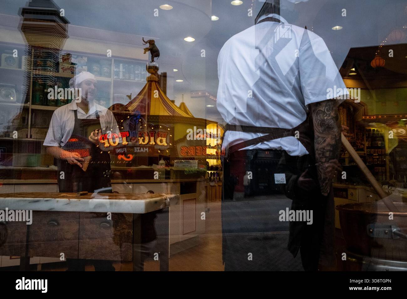 Workers prepare sweets inside the Big Top candy shop as reflections of ...