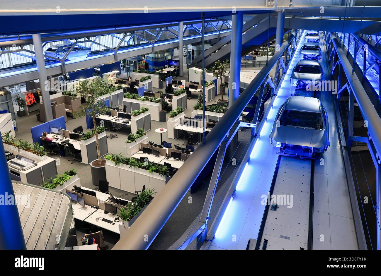 24 October 2025, Saxony, Leipzig: Bodies-in-white move across the office  workstations in the central building to the next production step at BMW  Group Plant Leipzig. Around 6800 employees currently produce the 1
