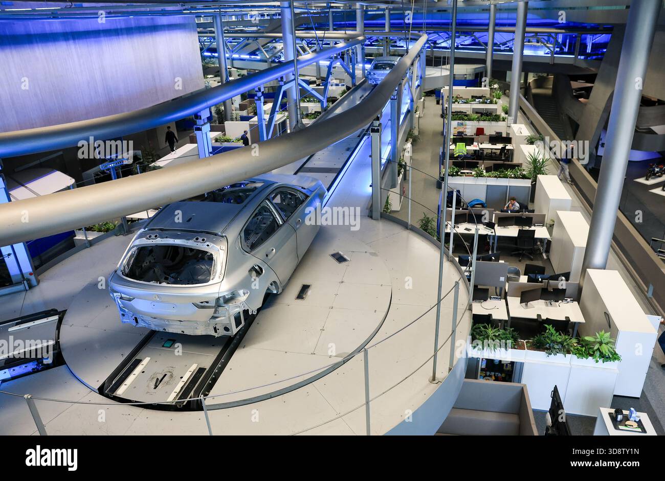 24 October 2025, Saxony, Leipzig: Bodies-in-white move across the office  workstations in the central building to the next production step at BMW  Group Plant Leipzig. Around 6800 employees currently produce the 1