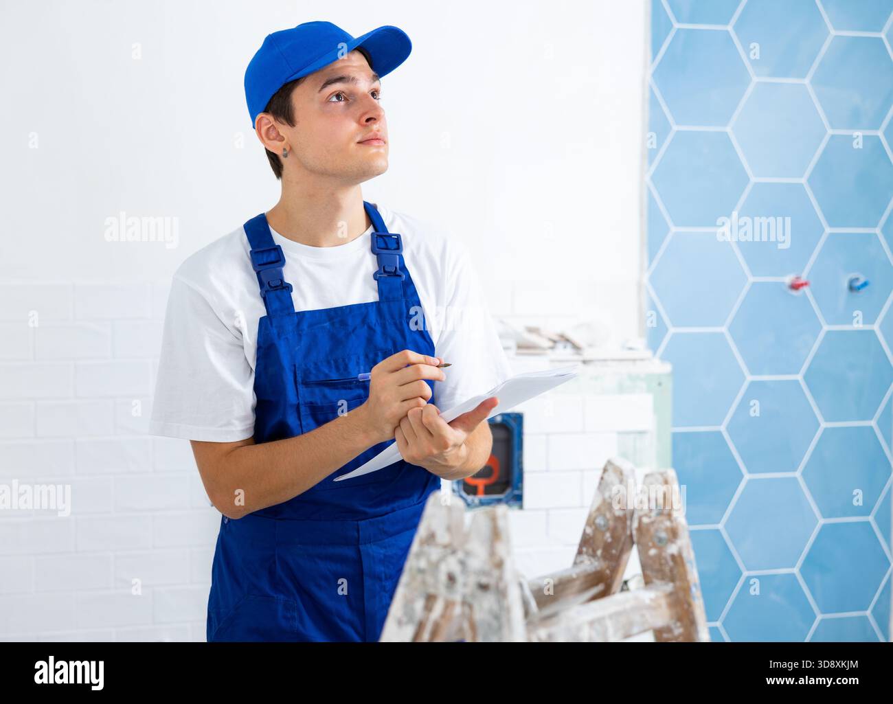 Focused contractor taking notes while planning renovation works in building Stock Photo