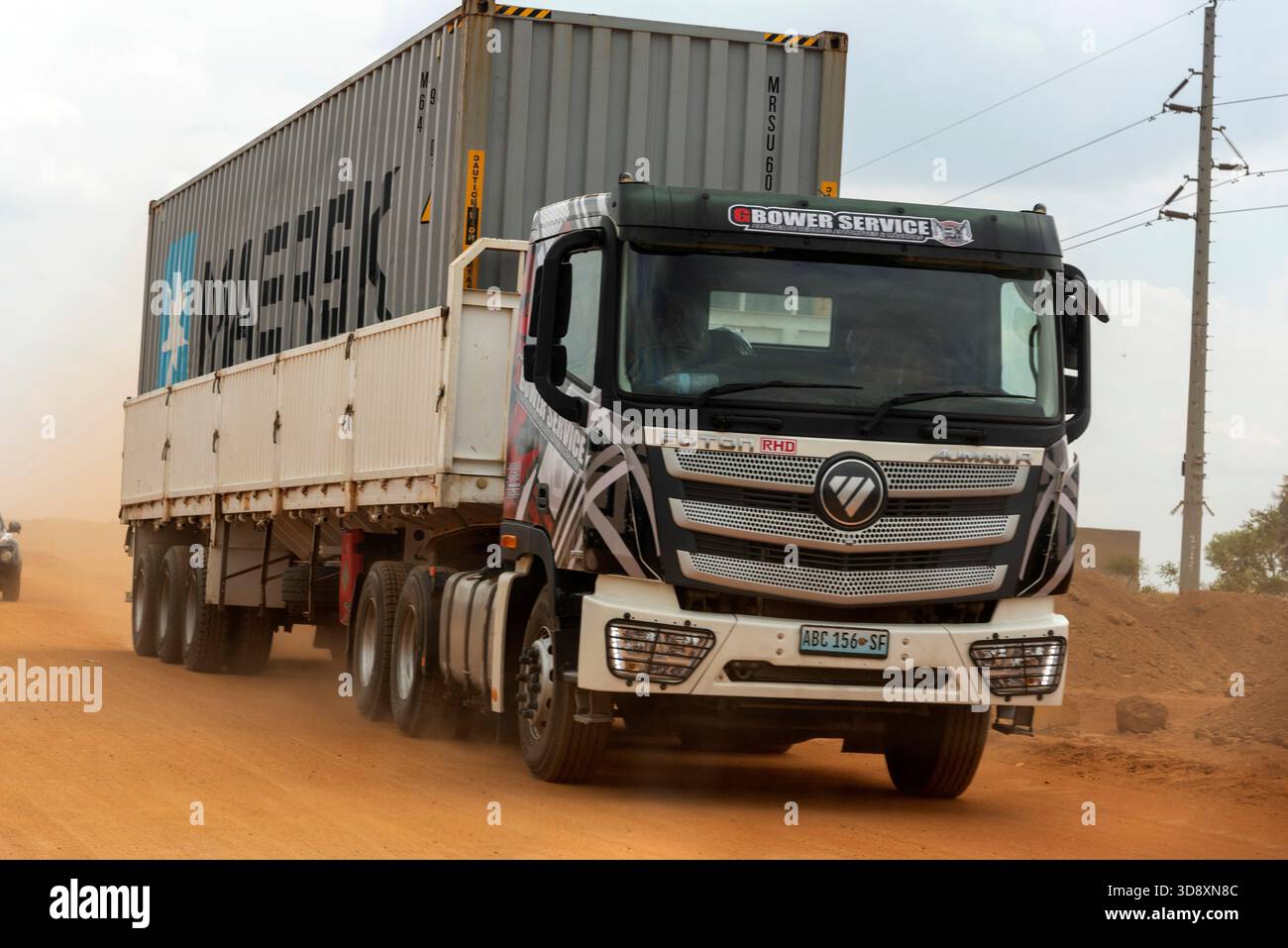 Lilongwe Malawi Africa.  09.11.2025.  Truck carrying a metal container travelling on an unmade road in Lilongwe Malaawi southern Africa. - Stock Image