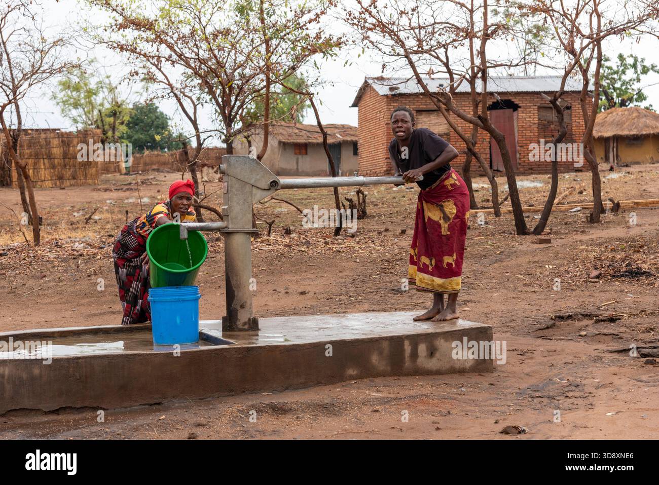 Salima Malawi southern Africa. 15.11.2025.  Malawian women dressed in colourful wrappers drawing fresh water by a borehole pump. - Stock Image