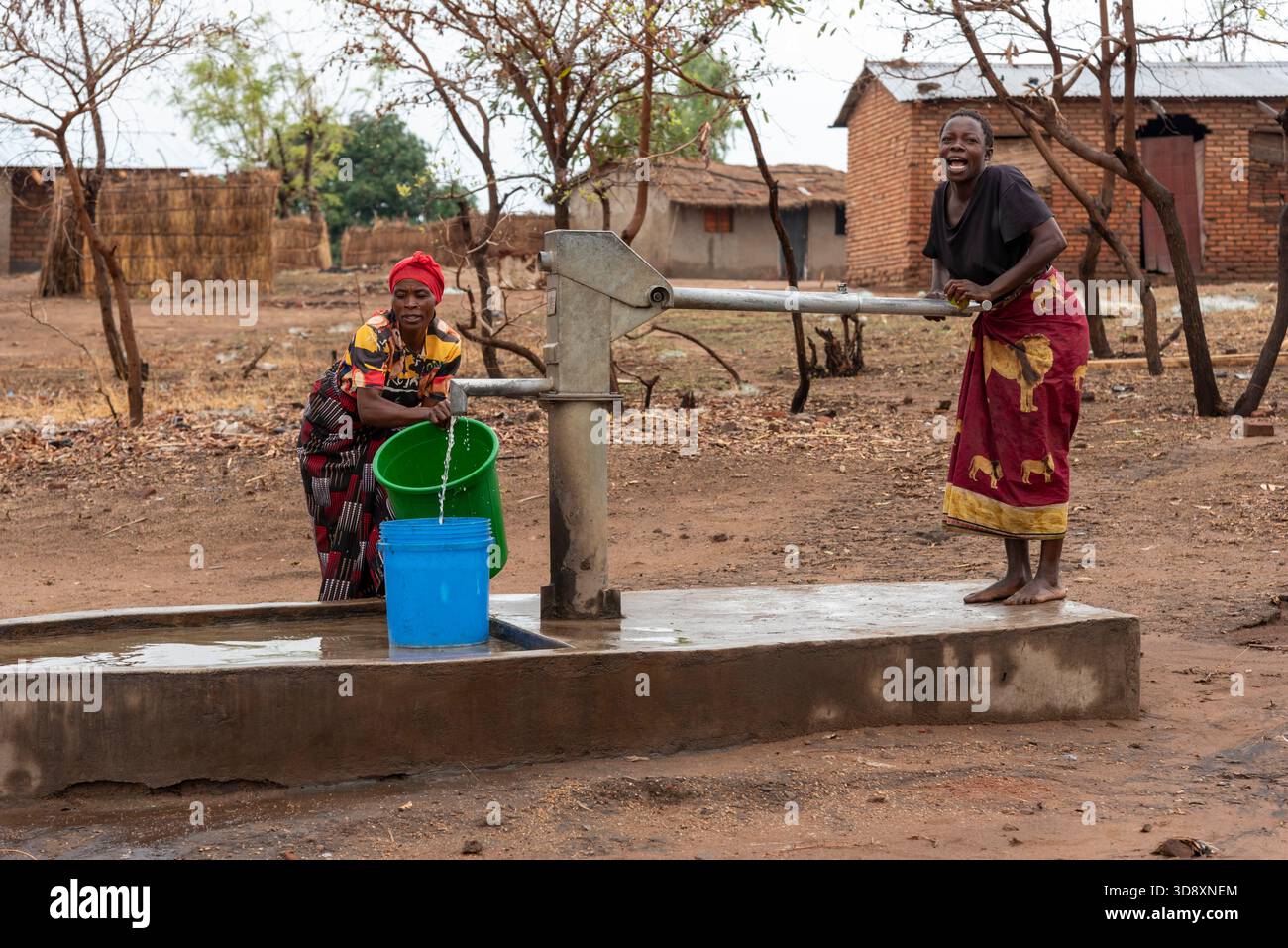 Salima Malawi southern Africa. 15.11.2025.  Malawian women dressed in colourful wrappers drawing fresh water by a borehole pump. - Stock Image