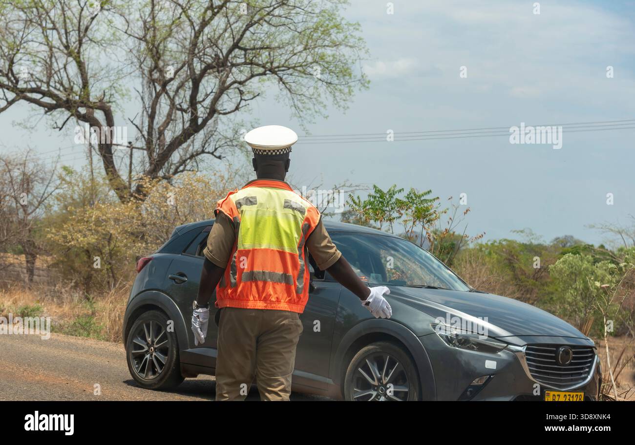Malawi ssouthern Africa. 19.11.2025. Police traffic officer in uniform with white gloves signals a motorist to stop. - Stock Image
