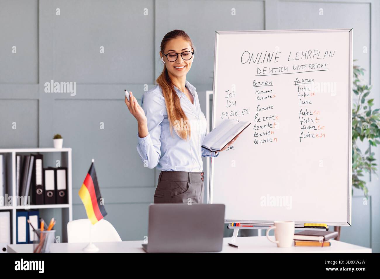 Teacher Explaining Online German Lesson Plan in a Bright Classroom Setting Stock Photo