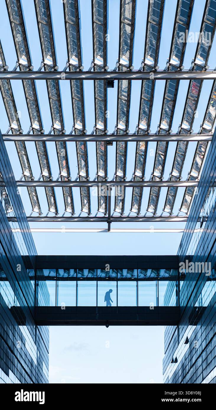 A man walks across an atrium at the Alan Turing Building, housing the ...