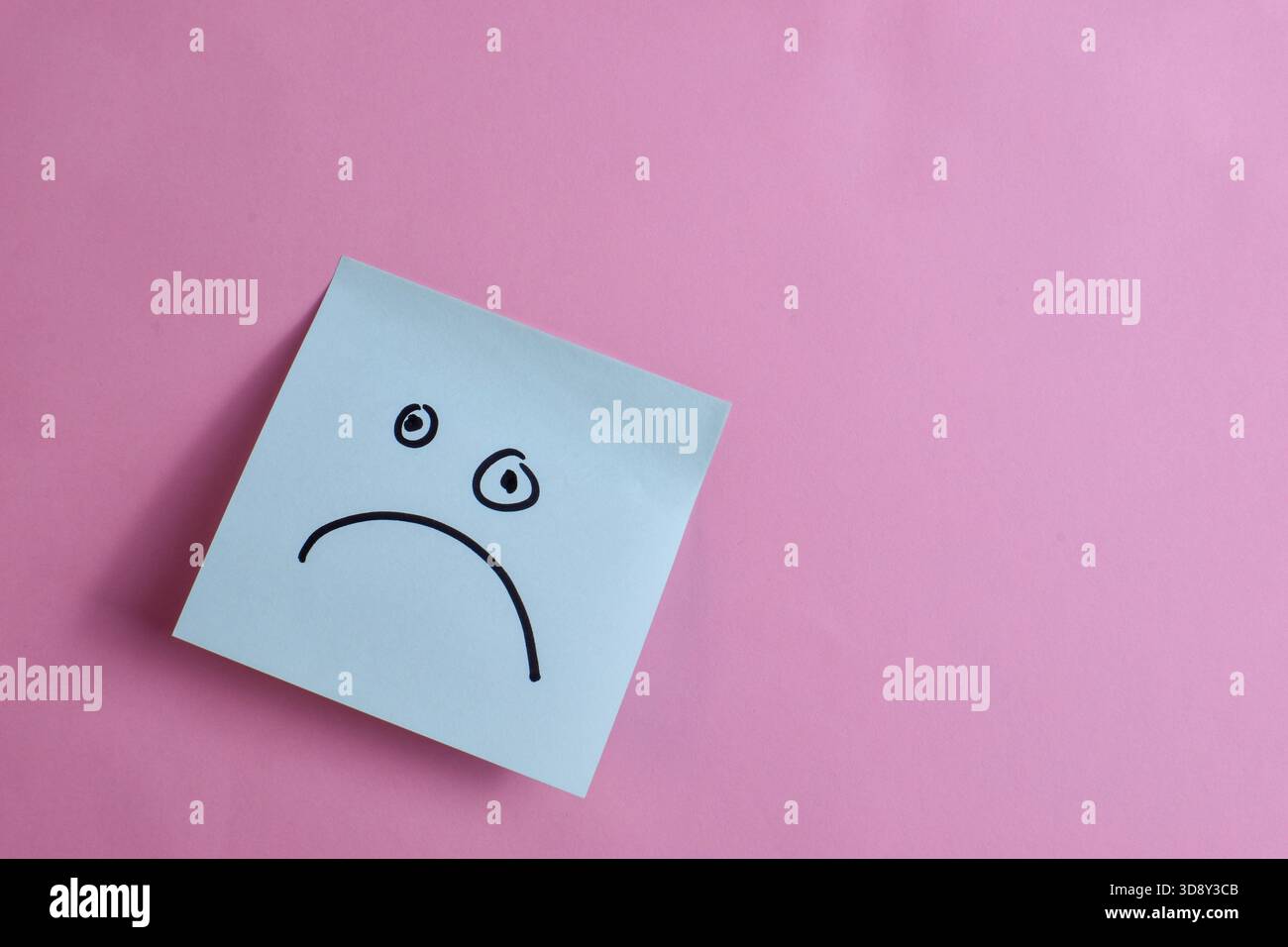 Light blue sticky note with sad face on pink background, expressing ...