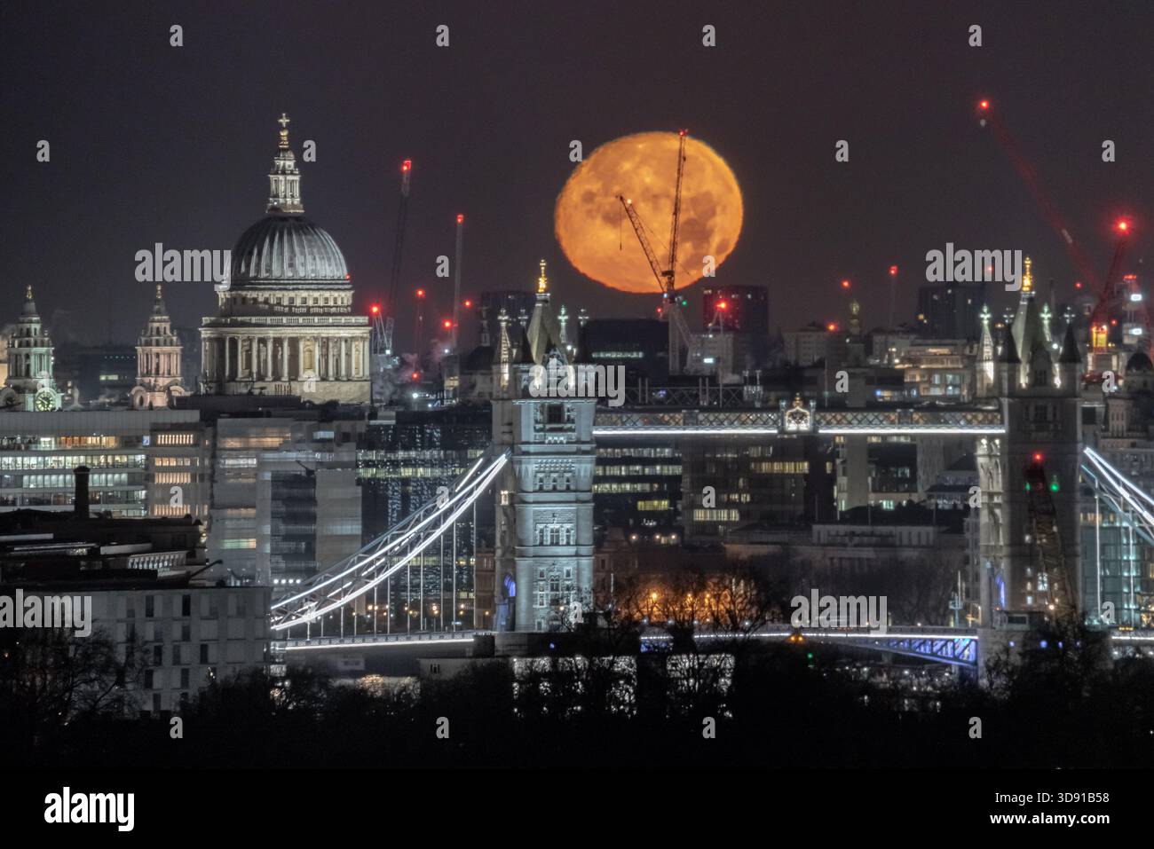 London, UK. 3rd December 2025. UK Weather:  ‘Cold Supermoon’ sets over the city. A nearly full (98.2%) Cold Moon, also the third consecutive (and final) supermoon of the year, sets in the early hours of Wednesday morning over St Paul's Cathedral and London Tower Bridge city landmarks. At its perigree - the point at which the moon is closest to Earth - the moon can appear 14% bigger and 30% brighter than the faintest moon of the year, according to NASA. Credit: Guy Corbishley/Alamy Live News Stock Photo