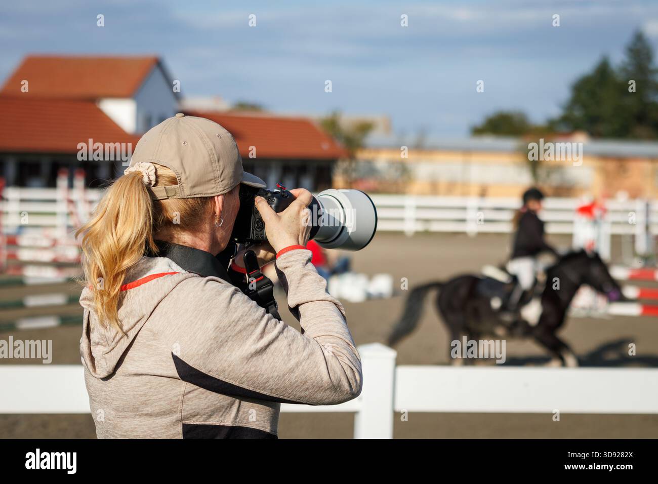 Sports photographer with camera and telephoto lens capturing equestrian show jumping. Photography themes Stock Photo