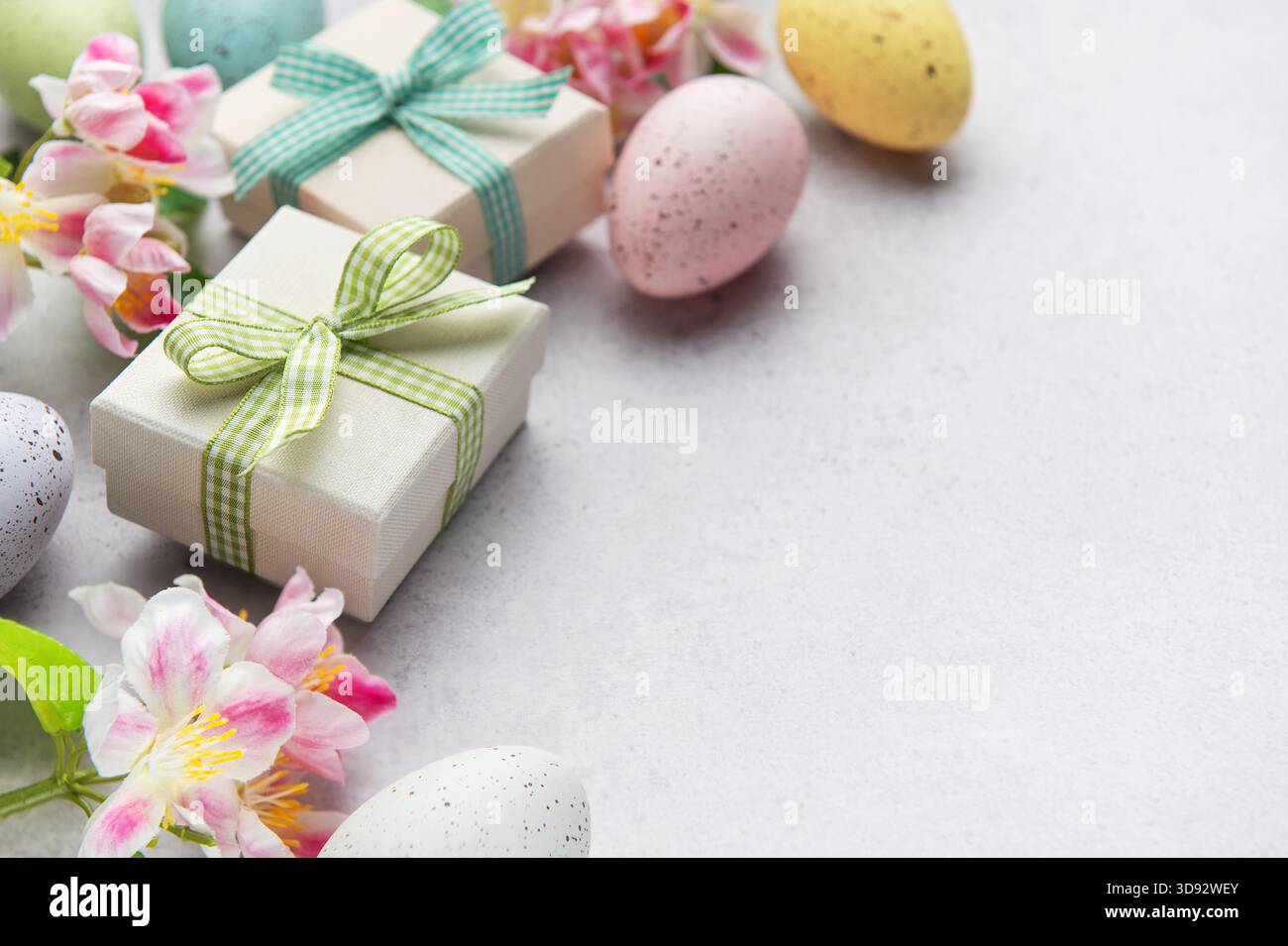 Pastel eggs and gift boxes with flowers on a light background Stock Photo
