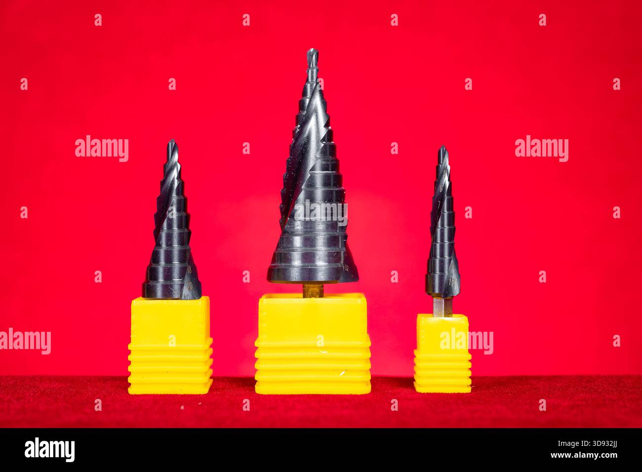 a set of conical step drill bits in various sizes on red at horizontal composition Stock Photo