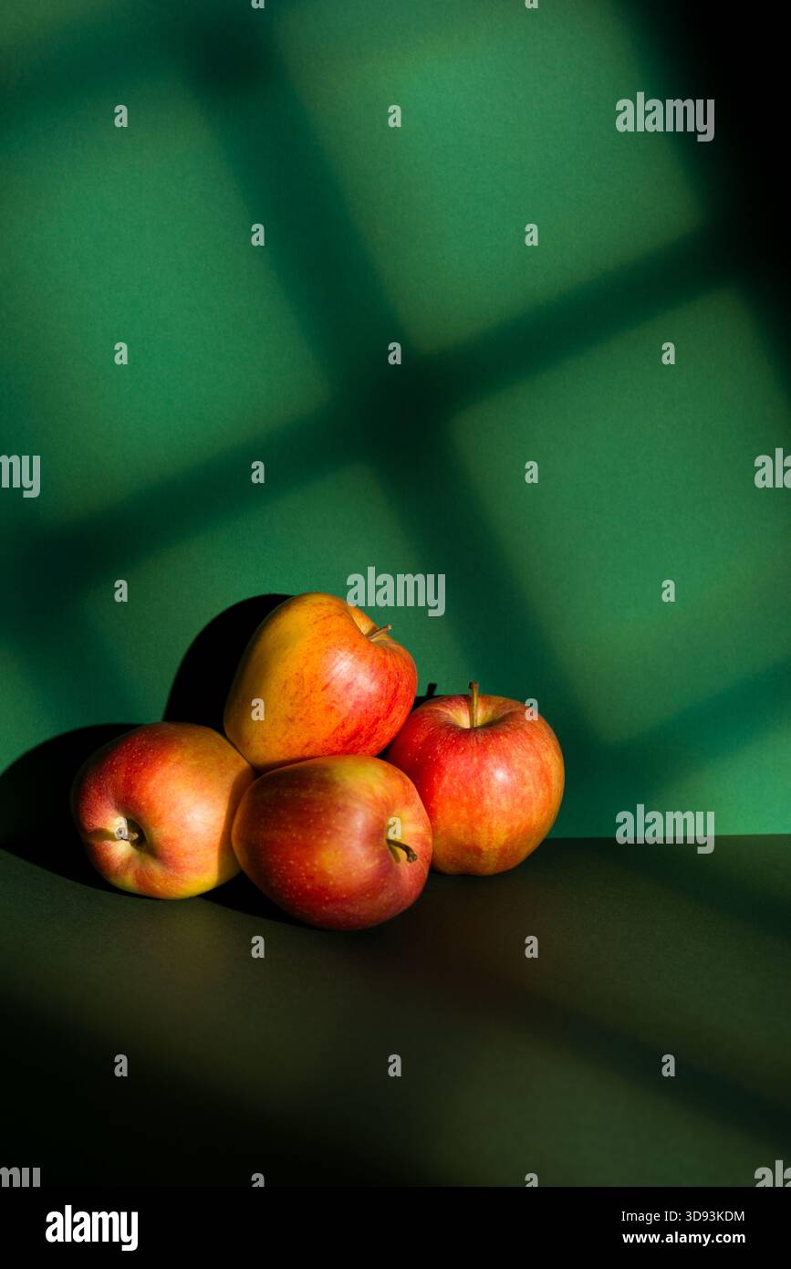 Apples pile on green background with window light effect. Stock Photo