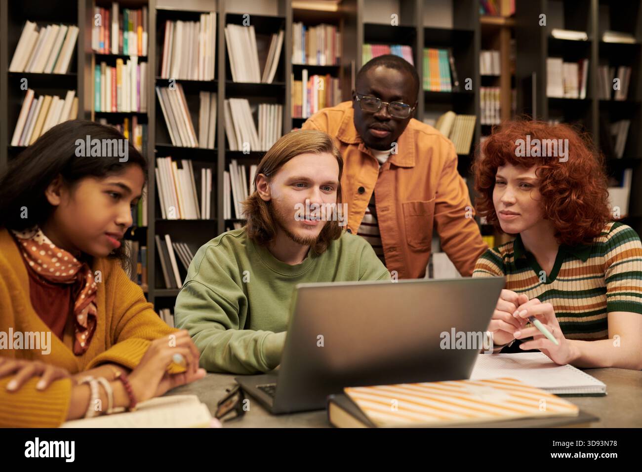 Diverse Young People Collaborating on Project in Library Setting Stock Photo