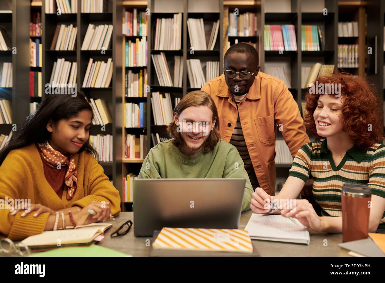 Multiethnic Young People Collaborating on Project in Library Setting Stock Photo
