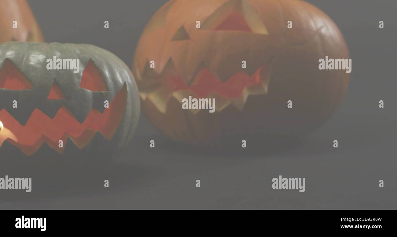 Glowing two carved pumpkins producing warm inner light on dark tabletop, soft reflections Stock Photo