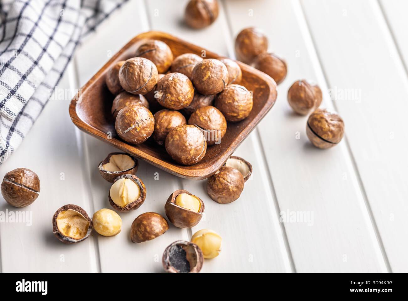 Tasty macadamia nuts in bowl on a white table. Stock Photo