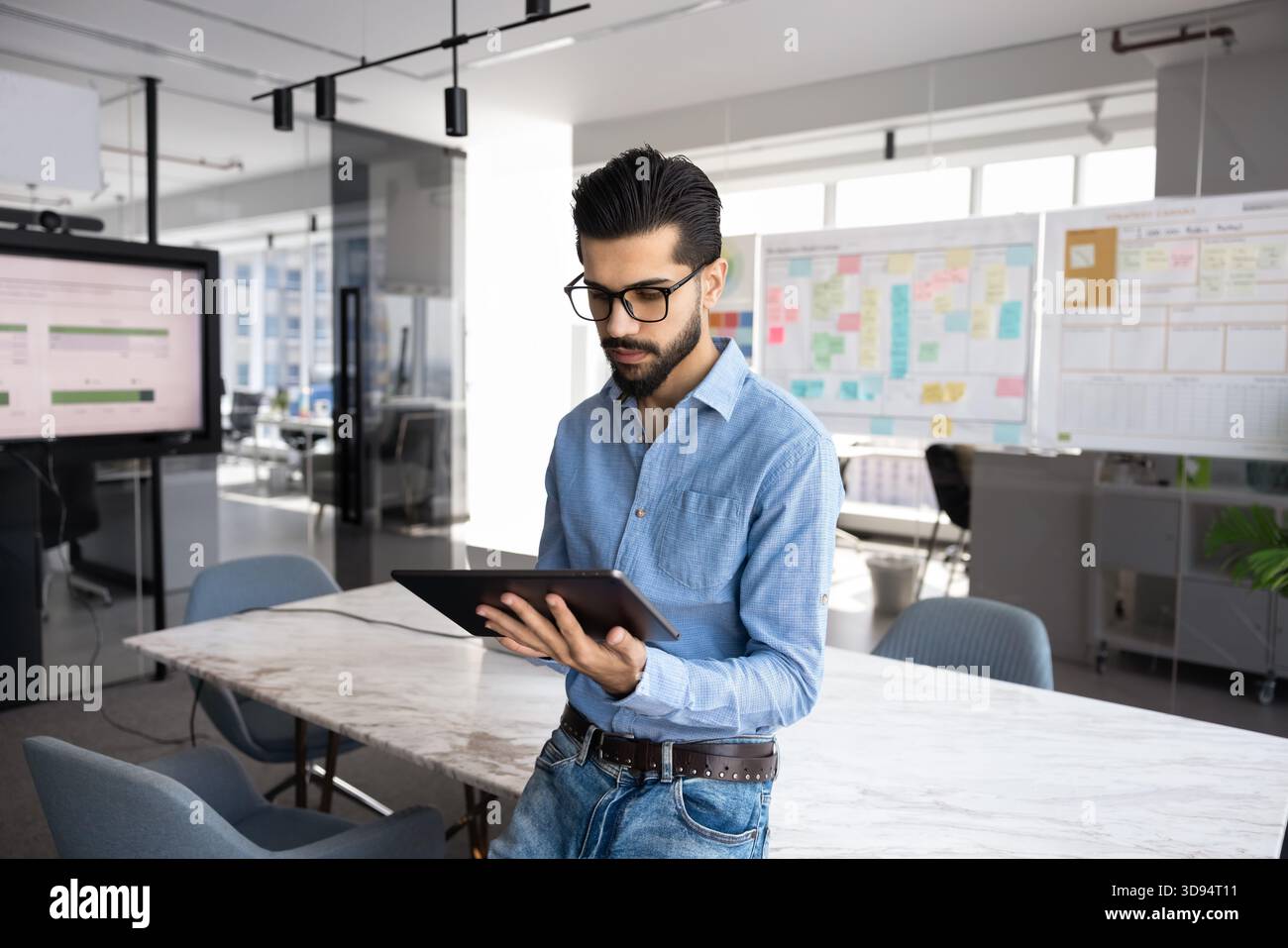 Serious young Middle Eastern startup leader man using tablet Stock Photo