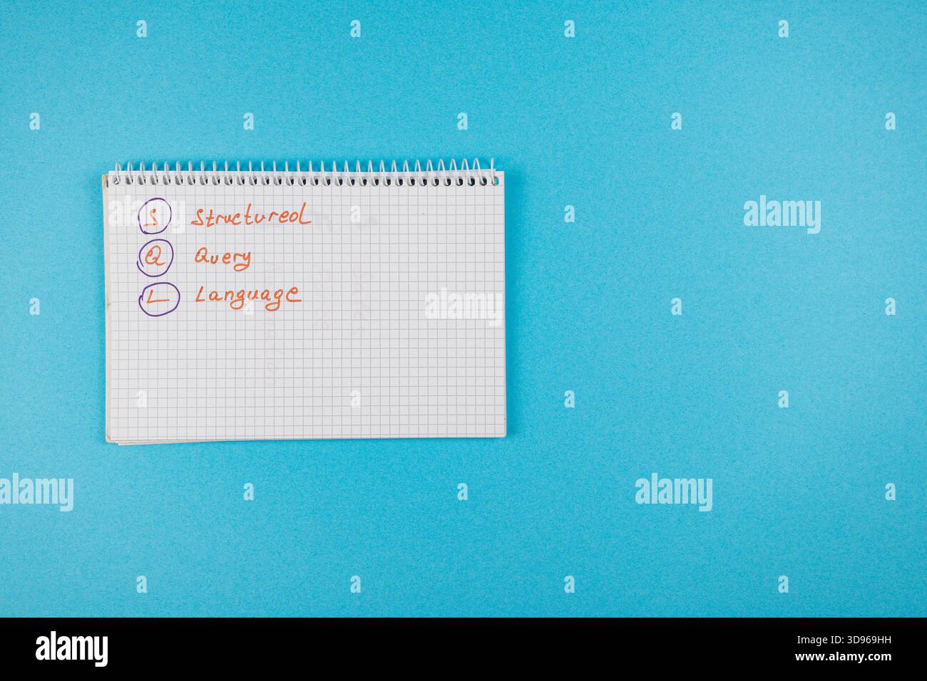 Handwritten notes on a notepad explain the concept of Structured Query Language on a bright blue background, highlighting its importance in programmin Stock Photo
