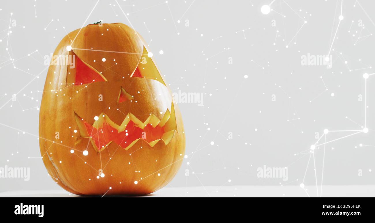 Sitting carved pumpkin glowing with orange-red light on white tabletop ...
