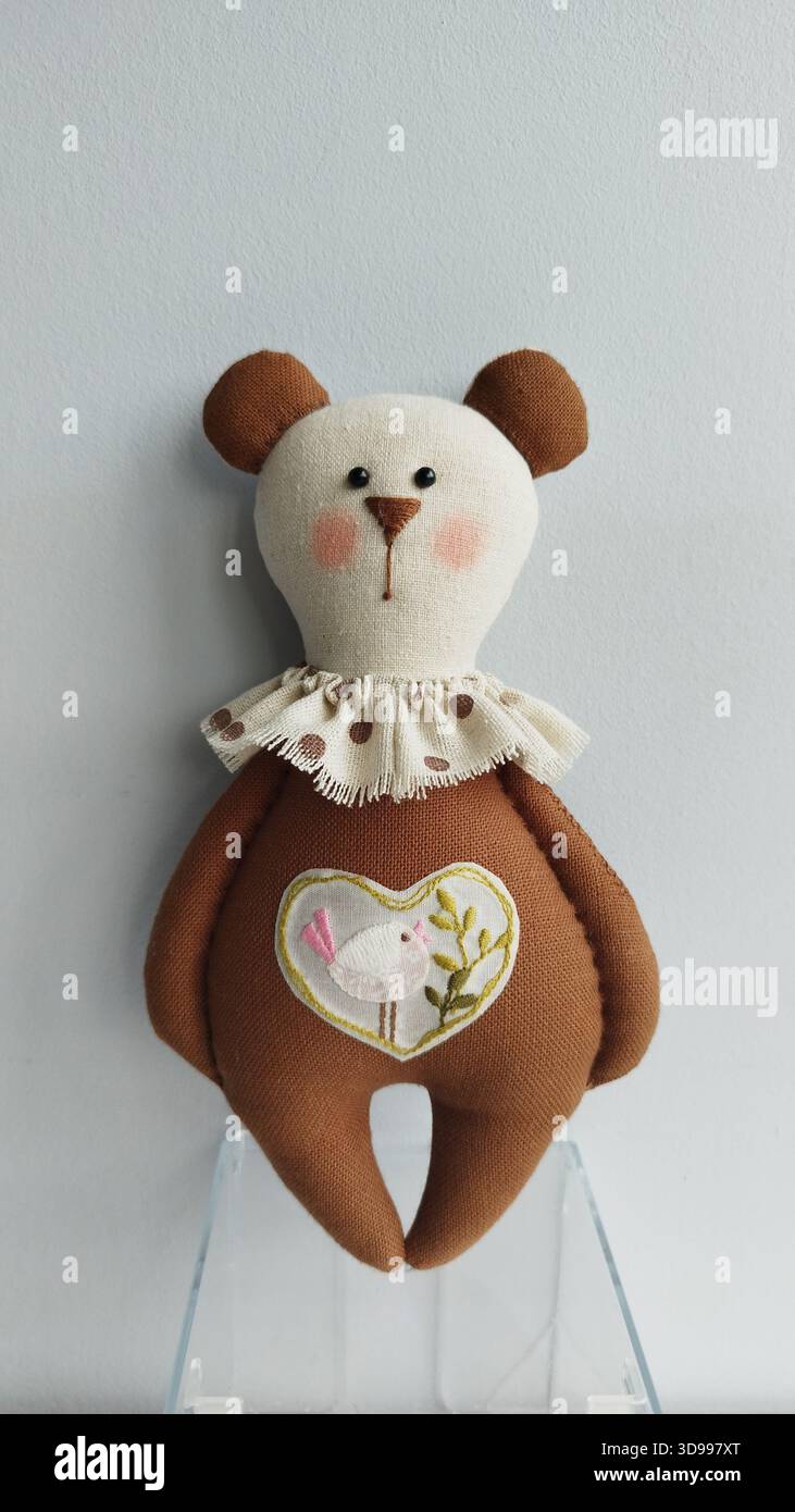 Soft handmade brown bear toy with lace collar and heart applique, simple studio look Stock Photo