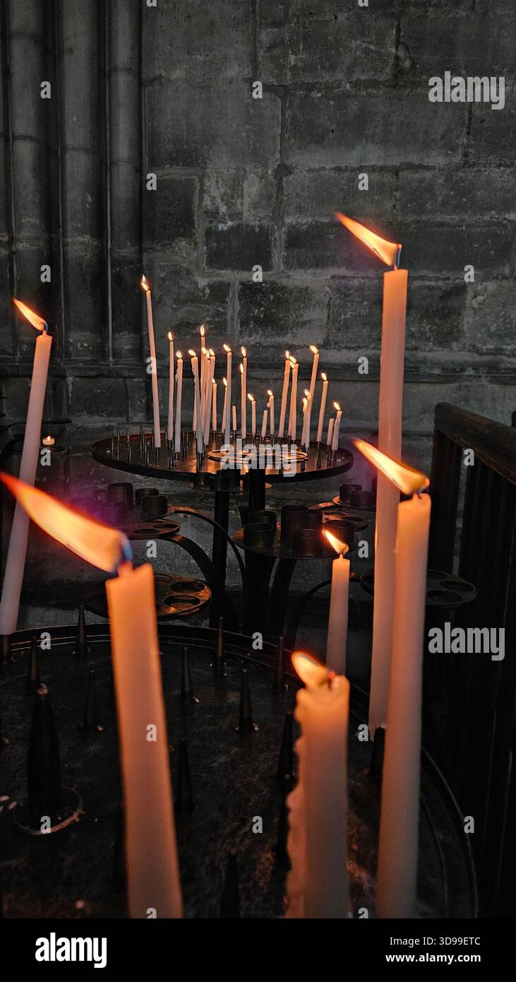 Lit candles on circular stand inside stone-walled church, creating a solemn and contemplative atmosphere - Smartphone Captured Stock Image