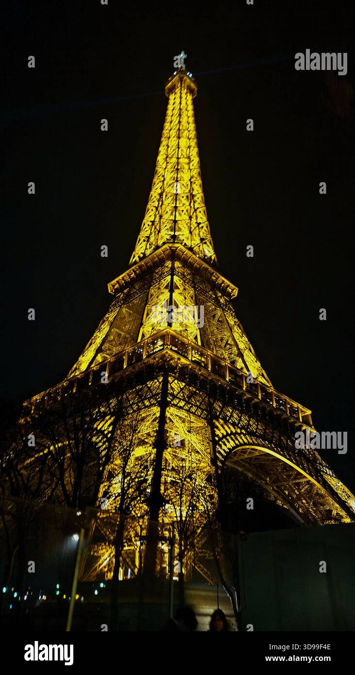 Eiffel Tower illuminated at night in Paris, France, with golden lights and dramatic low-angle view. - Smartphone Captured Stock Image