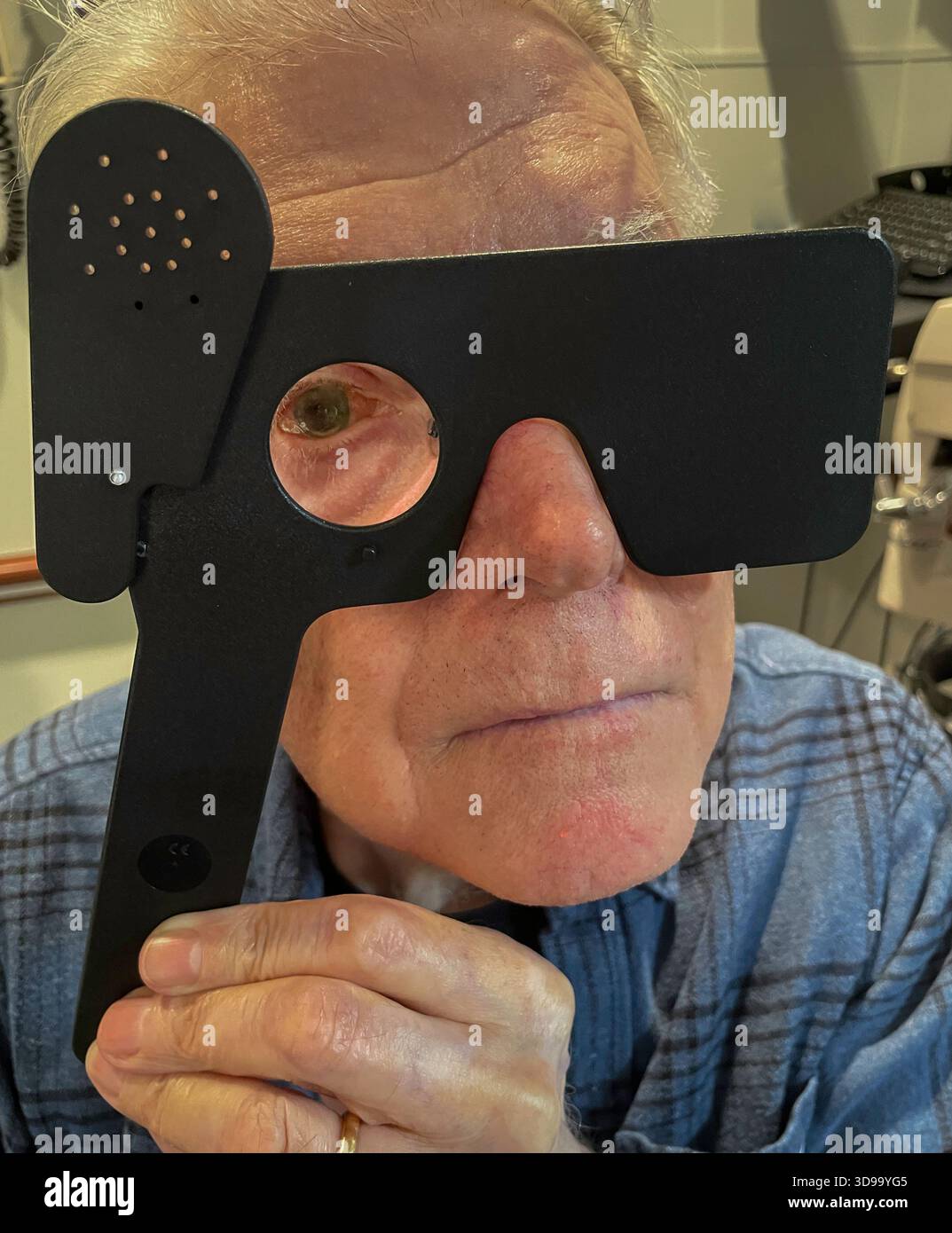 Senior man testing his sight with an occluder during a vision exam at the ophthalmologist, 2025, New York City, United States - Smartphone Captured Stock Image