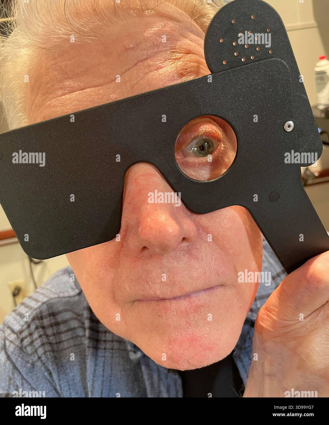 Senior man testing his sight with an occluder during a vision exam at the ophthalmologist, 2025, New York City, United States - Smartphone Captured Stock Image