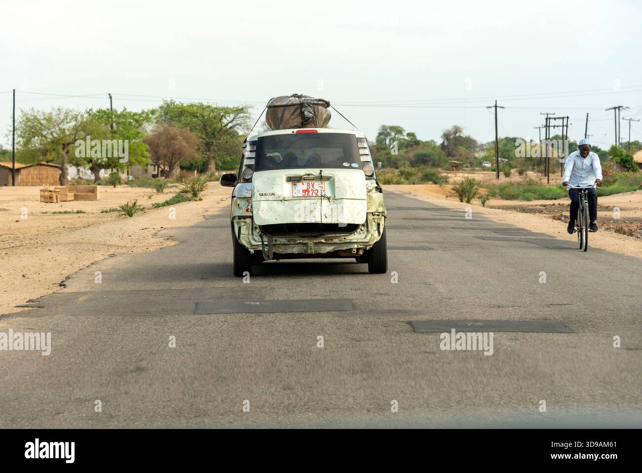 Southern Malawi Africa.  Following a badly damaged taxi  with plastic covered baggage on the roof on a highway in southern Malawi Africa - Stock Image
