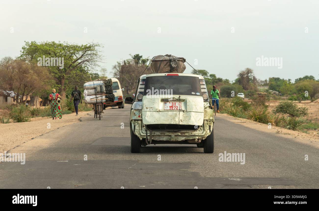 Southern Malawi Africa.  Following a badly damaged taxi  with plastic covered baggage on the roof on a highway in southern Malawi Africa - Stock Image