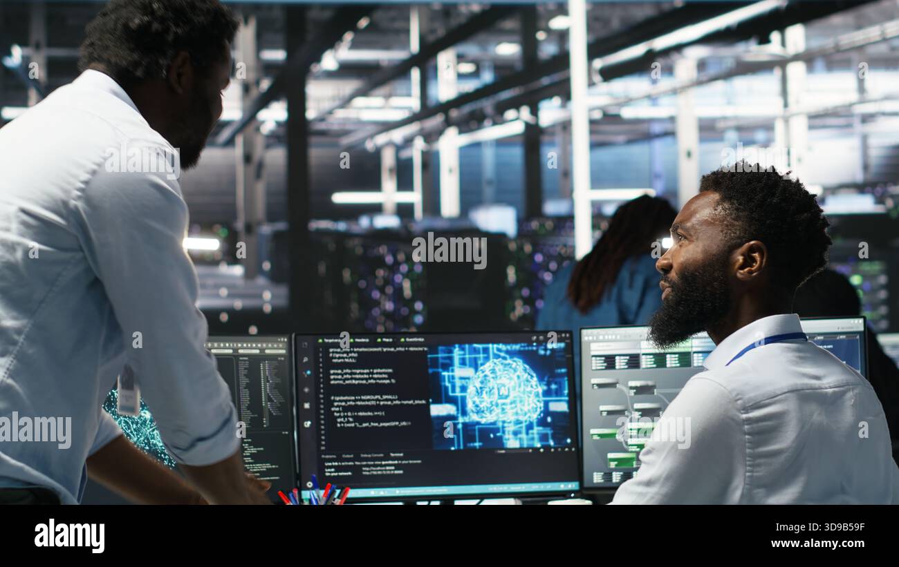 Server hub manager checking AI generated data analytics graphs, congratulating worker. Data center team leader doing fist bump with admin using artificial intelligence showing system metrics, camera B Stock Photo