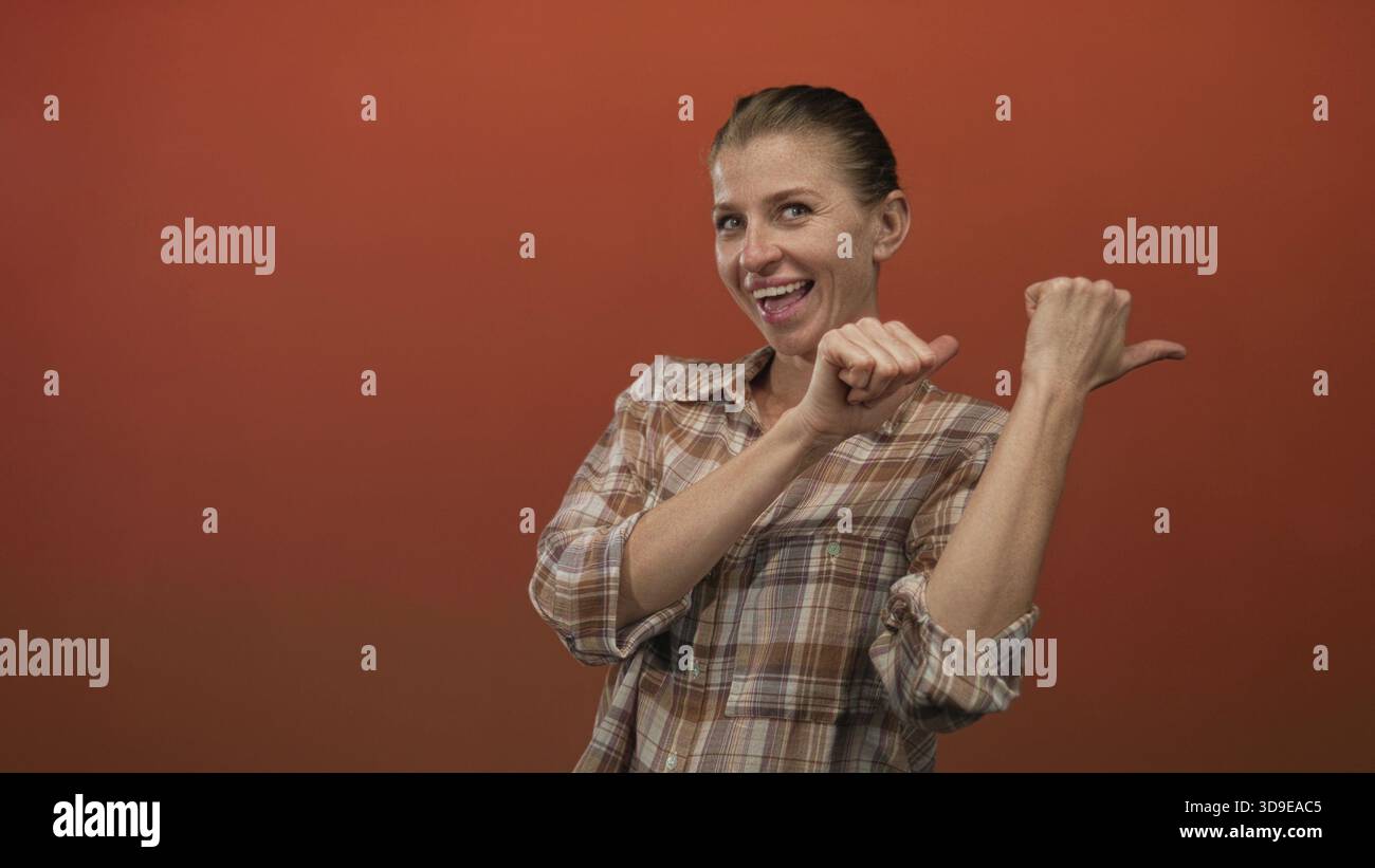 Woman in plaid shirt pointing thumb to side, visible hands and smiling ...