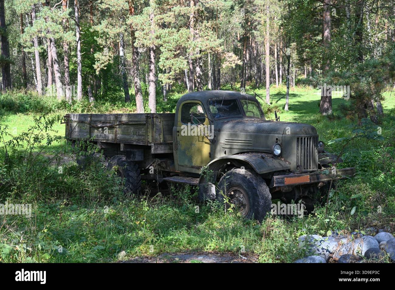 An old abandoned Soviet truck stands in a forest overgrown with grass ...