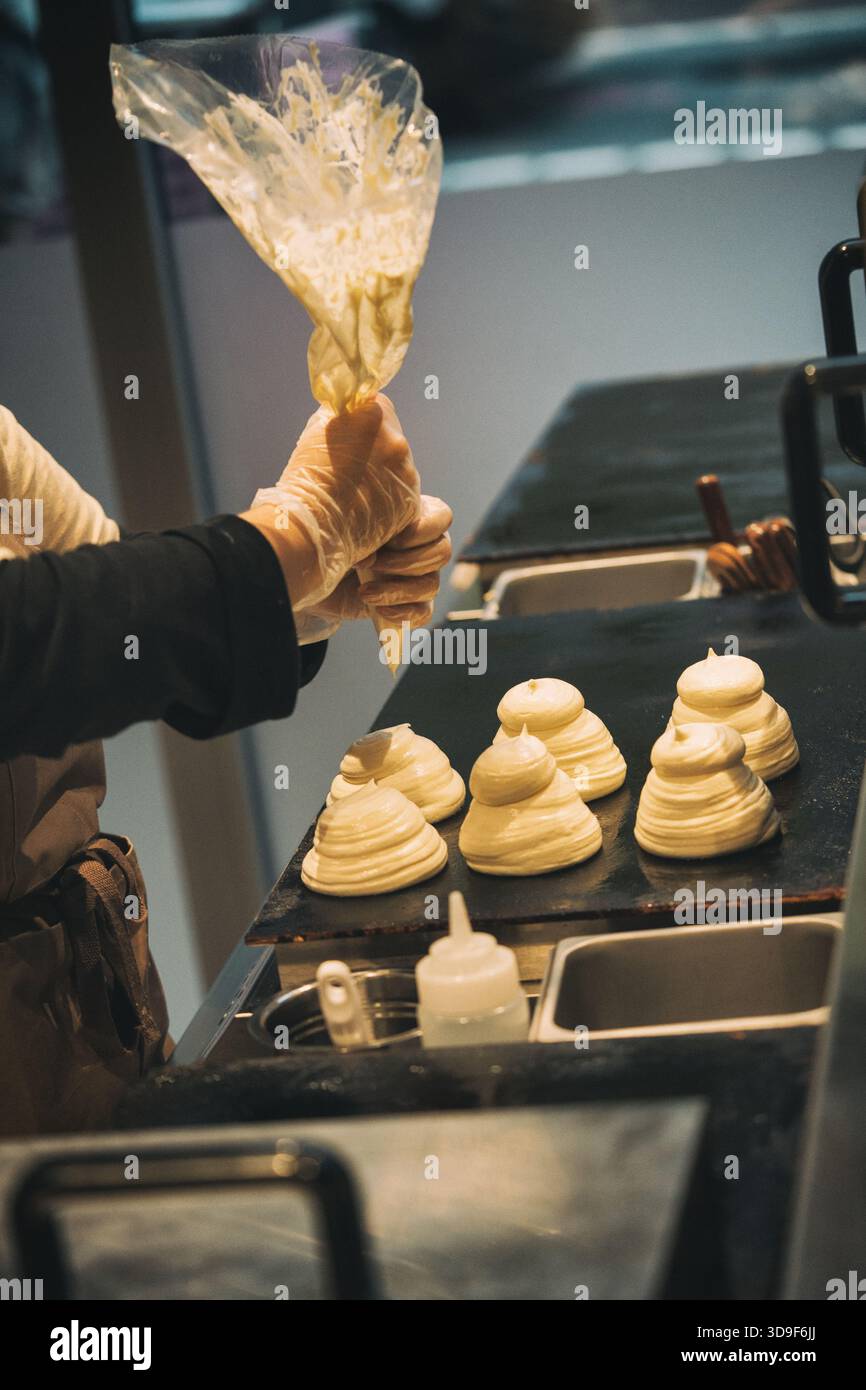 woman squeezing japanese pancake batter onto a hot plate in a cafe Stock Photo