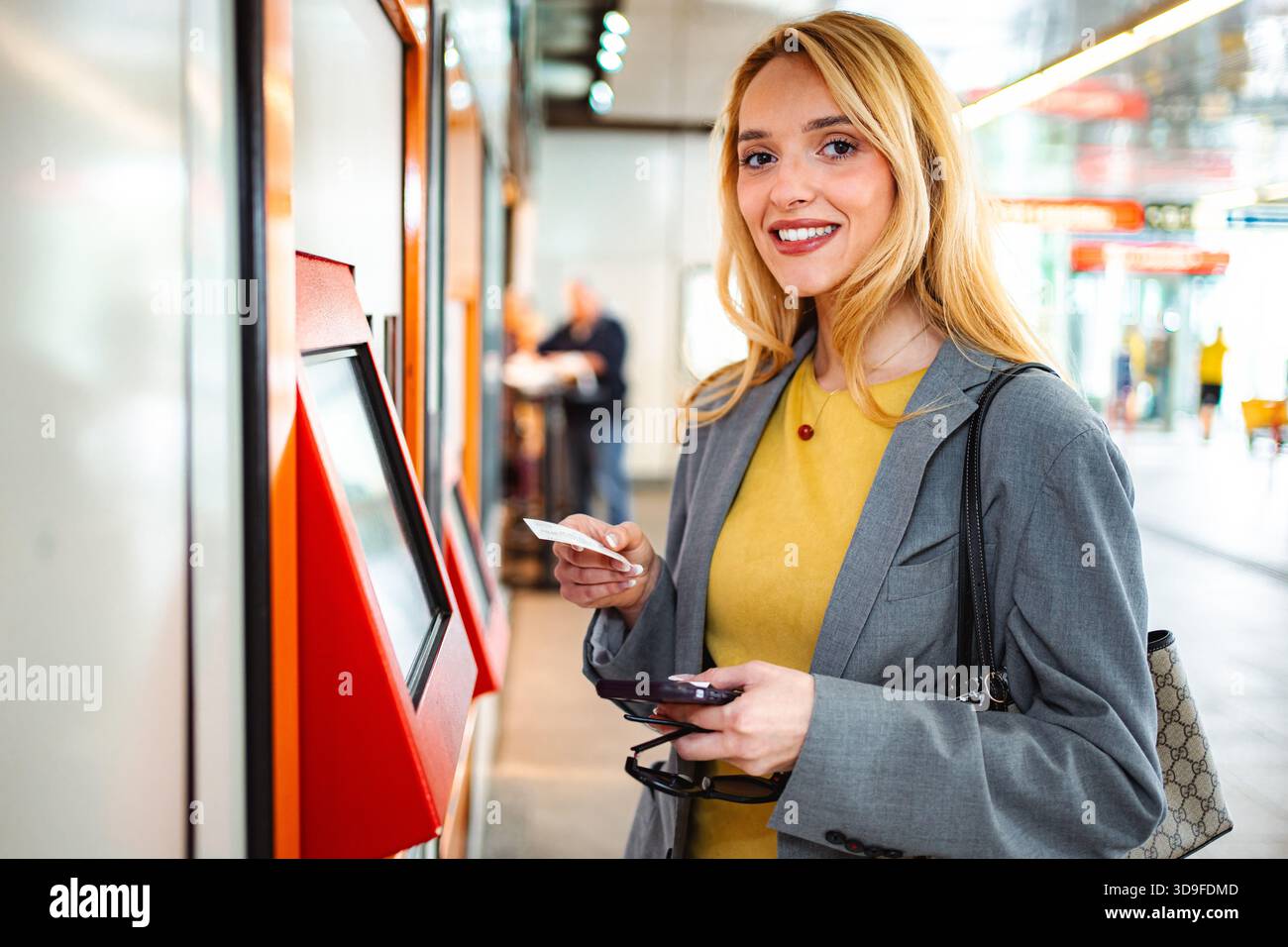 Woman smiling buying ticket with credit card at station Stock Photo - Alamy