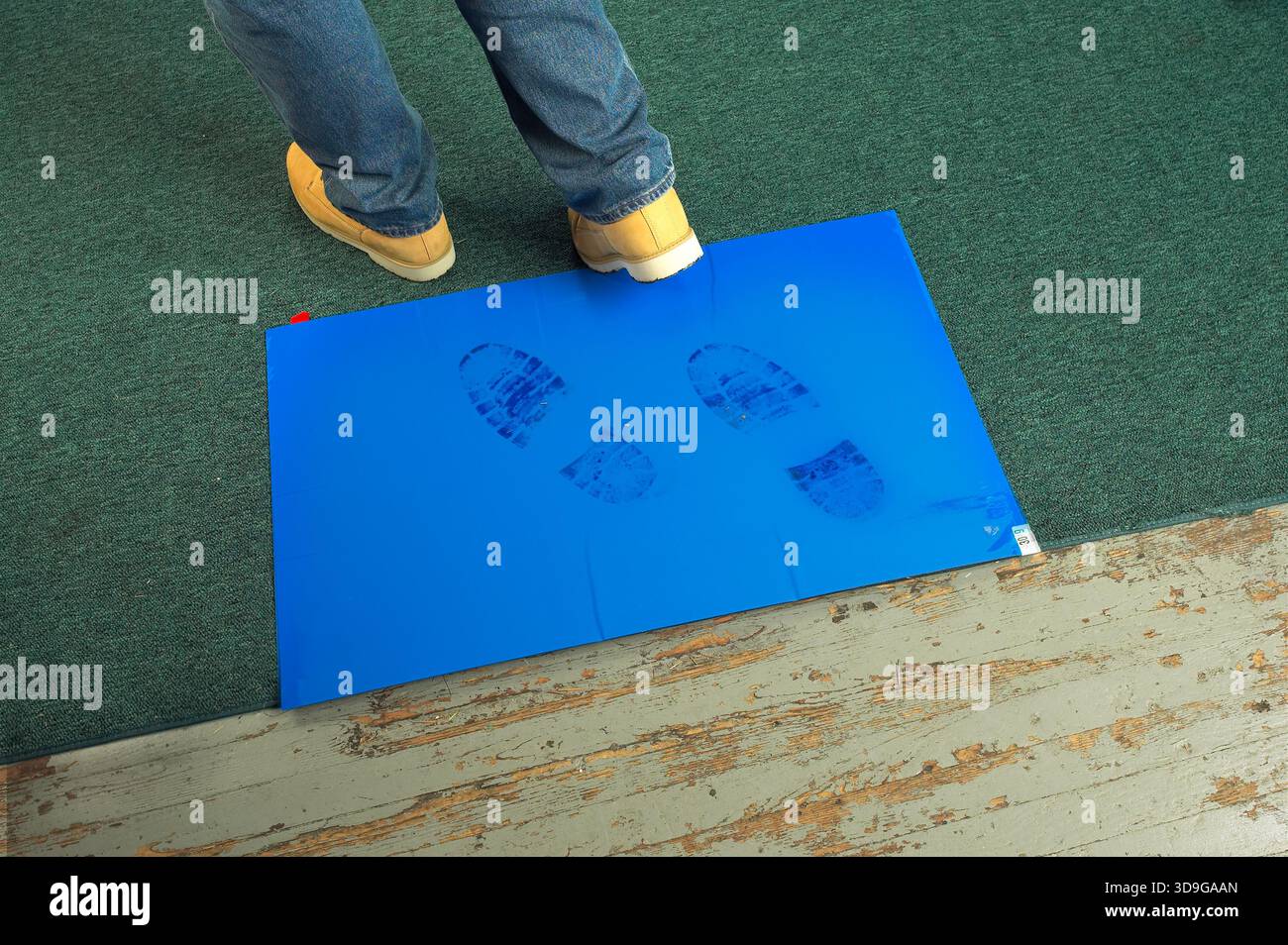 Worker walking in to job site using sticky tacky clean mat, USA Stock Photo