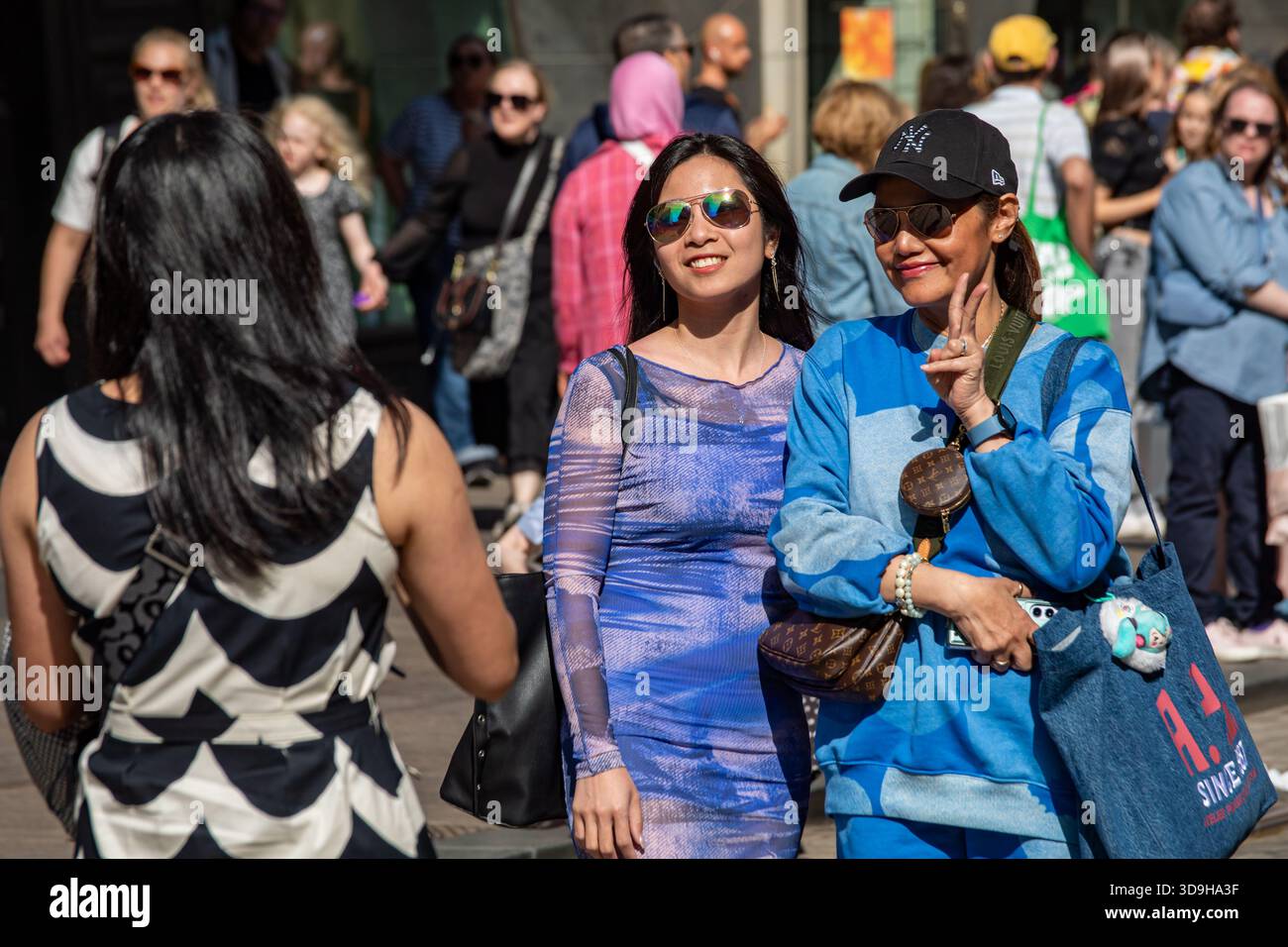 Women posing for photograph on Aleksanterinkatu in Kluuvi district of Helsinki, Finland Stock Photo