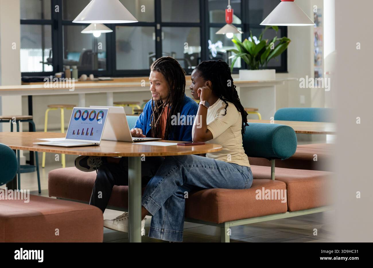 African American coworkers collaborating at modern coworking lounge using laptop smartphone papers Stock Photo