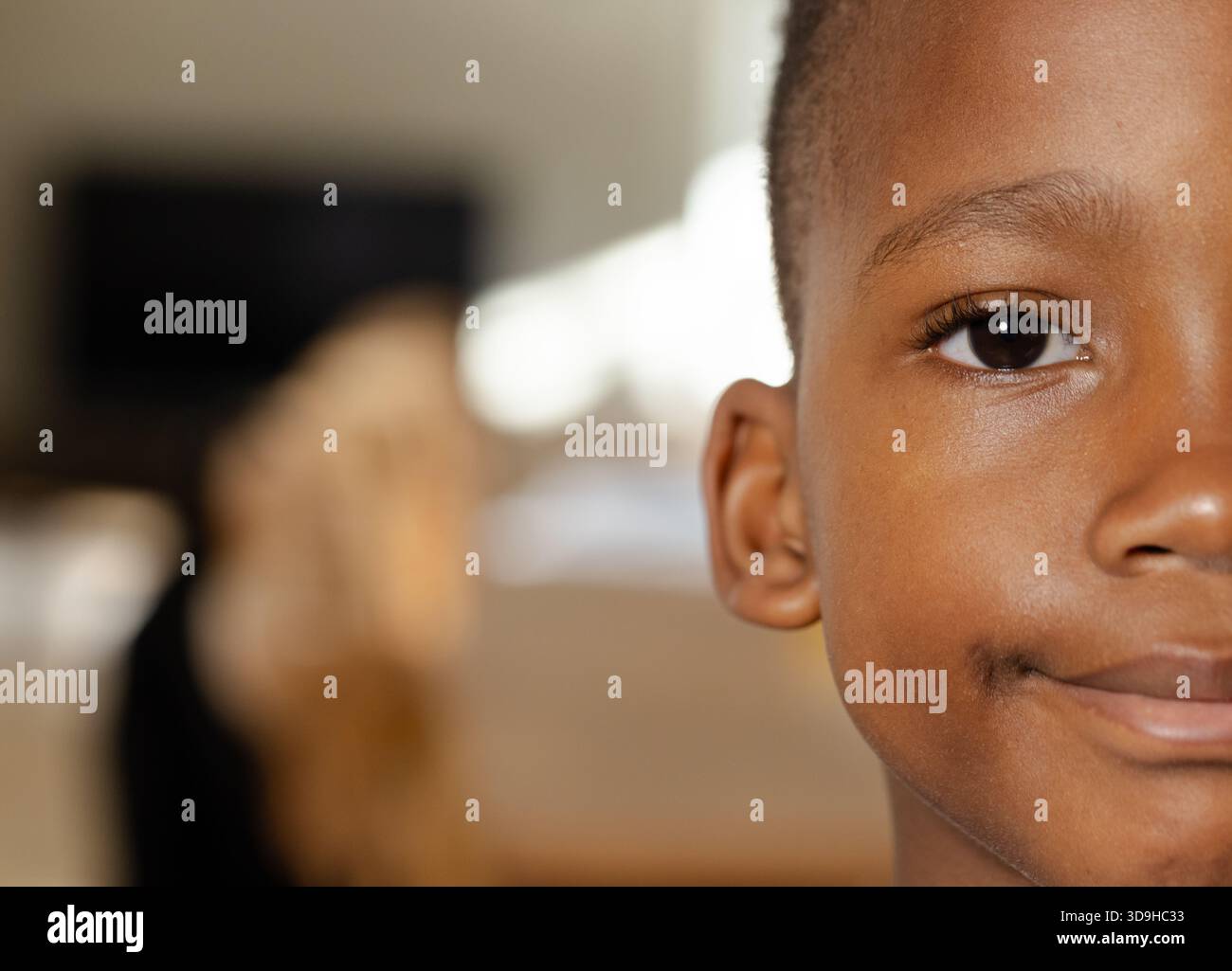 African American child boy smiling gently while sitting on sofa at home with golden dog Stock Photo