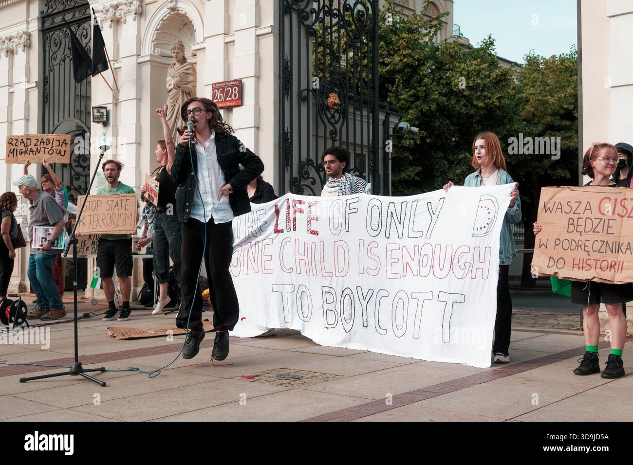 Protesters hold signs and a large banner while a speaker addresses the crowd during a pro-Palestine rally. Stock Photo