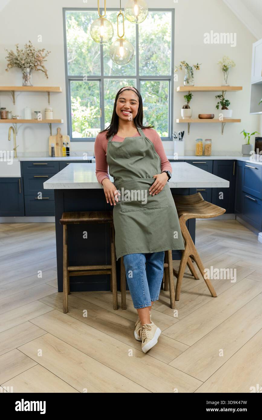 Asian woman chopping vegetables at home marble kitchen island by glass pendant lights Stock Photo