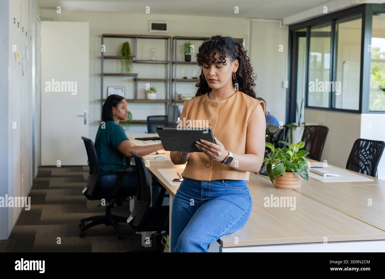 African American coworkers working in open office, woman in tan blouse holding tablet, copy space Stock Photo