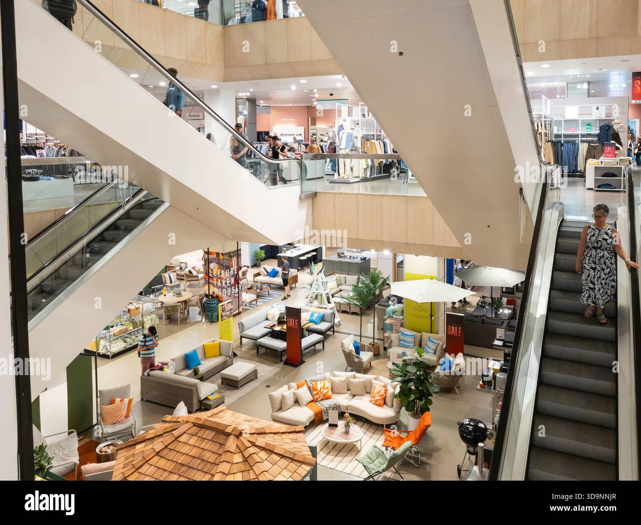 Escalators between floors in John Lewis department store, Broad Street, Reading, looking down on an open plan floor with seasonal garden furniture, UK - Smartphone Captured Stock Image