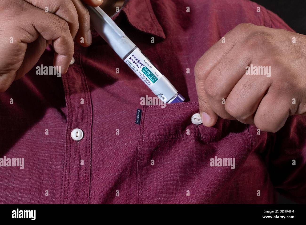 Close-up of a man putting a Mounjaro KwikPen, a diabetes and weight-loss medication, into his casual shirt pocket. Stock Photo