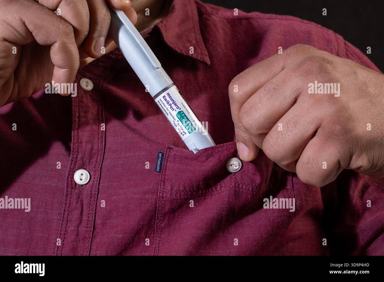 Close-up of a man putting a Mounjaro KwikPen, a diabetes and weight-loss medication, into his casual shirt pocket. Stock Photo