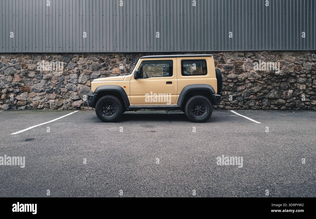 beige Suzuki Jimny in side street (wide image). Side profile view