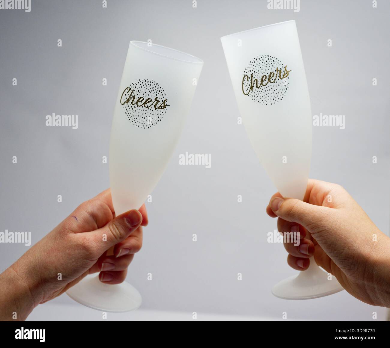 Two frosted cheers glasses are raised for a festive toast, creating a ...