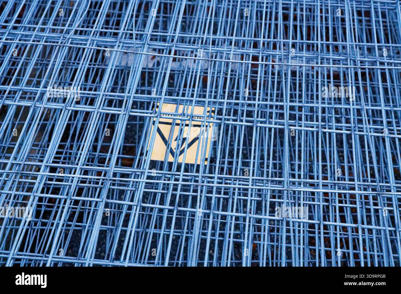 Bundles of wire panels are stacked in a yard, their grids aligned in ...